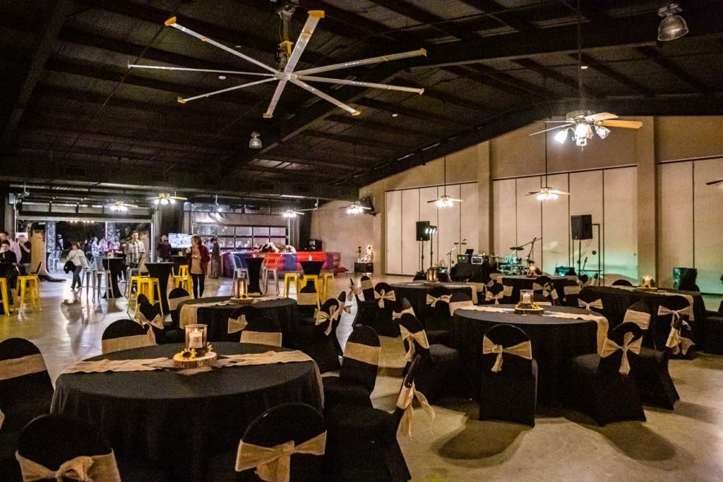 fully decorated room with tables chairs stage and people